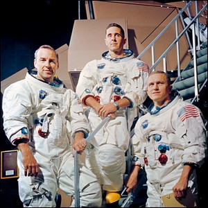 portrait photo of three American astronauts wearing spacesuits without helmets