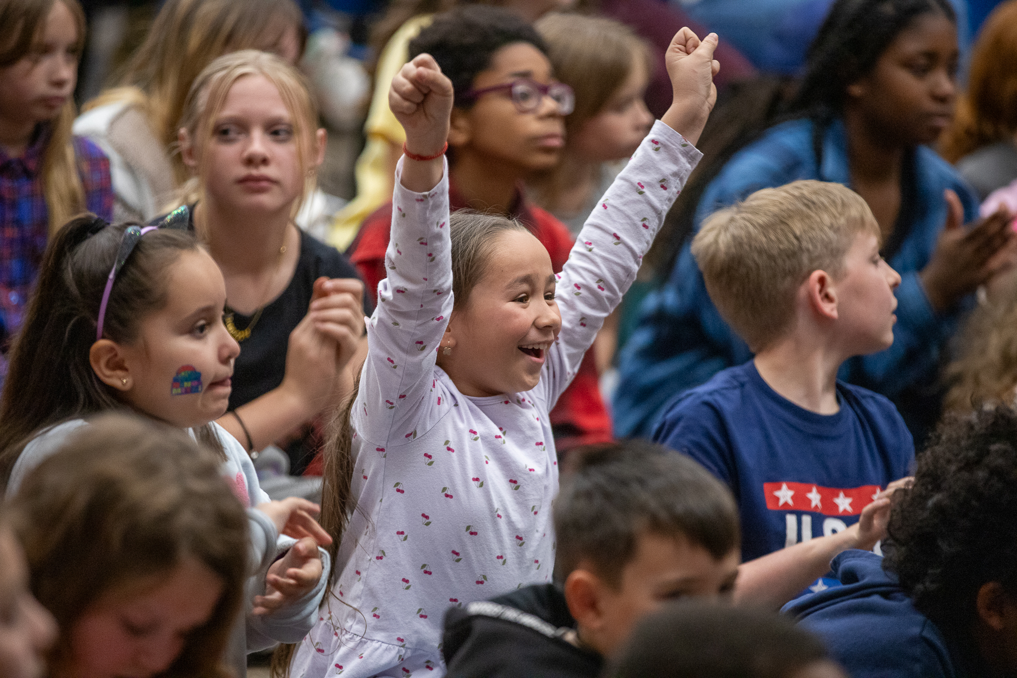 A little girl holds her arms up in the air in a cheer