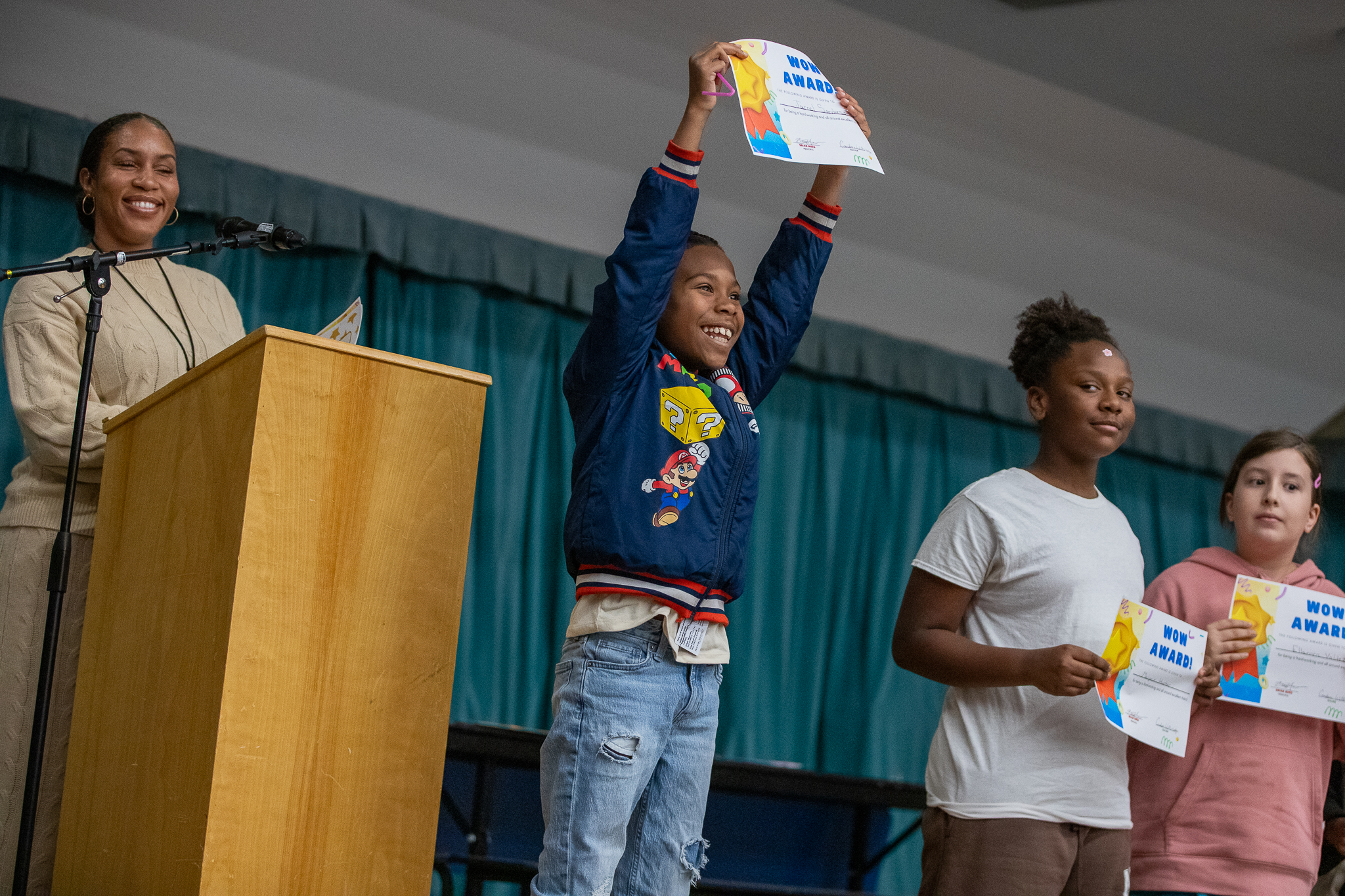 A little boy excitedly holds his award certificate over his head