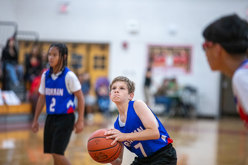 A boy in a blue jersey concentrates as he's about to shoot a basket