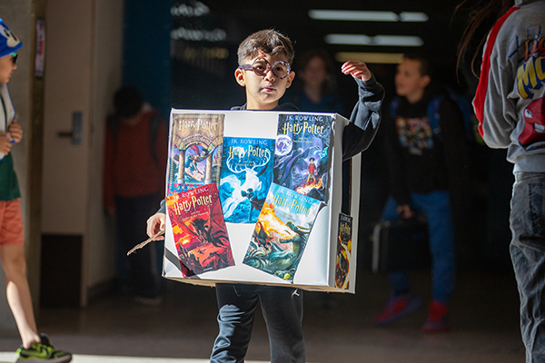 A boy wearing glasses and a diorama with Harry Potter book covers