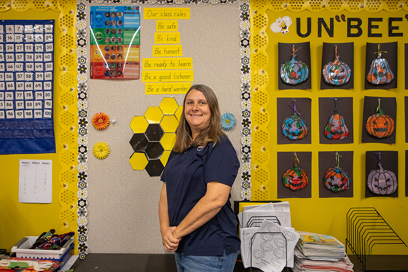 A woman smiles in front of colorful classroom walls